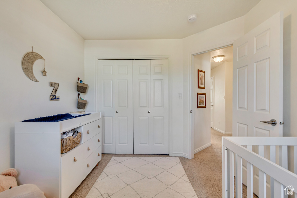 Bedroom featuring baseboards, a closet, and light colored carpet