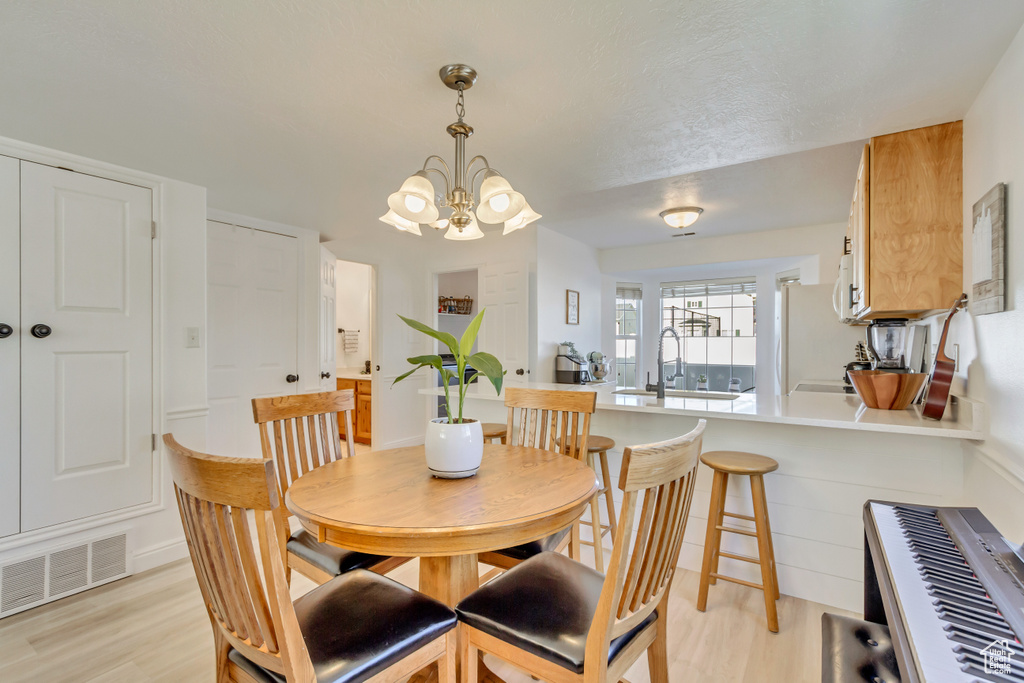 Dining room featuring light wood finished floors, an inviting chandelier, and visible vents