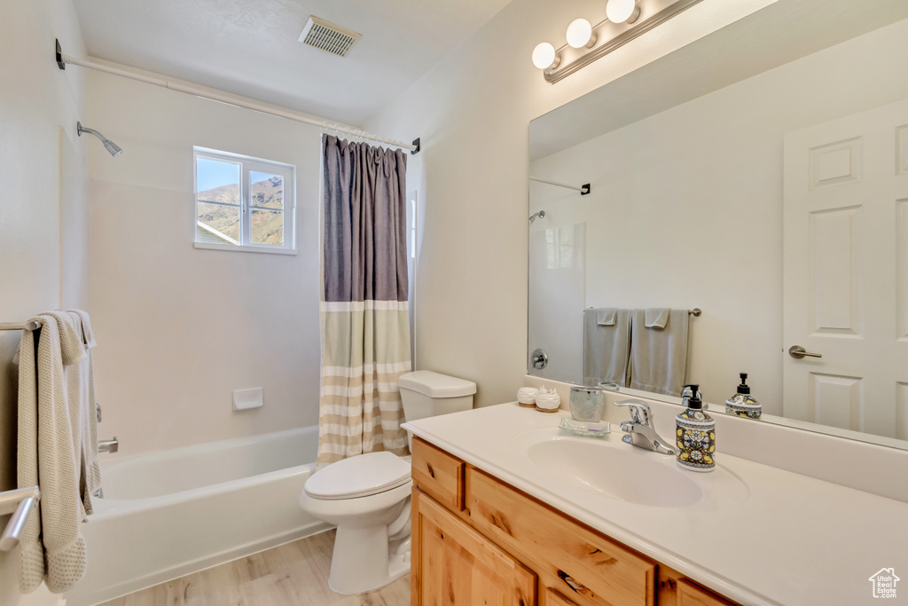 Full bathroom featuring toilet, wood finished floors, vanity, visible vents, and shower / bath combination with curtain