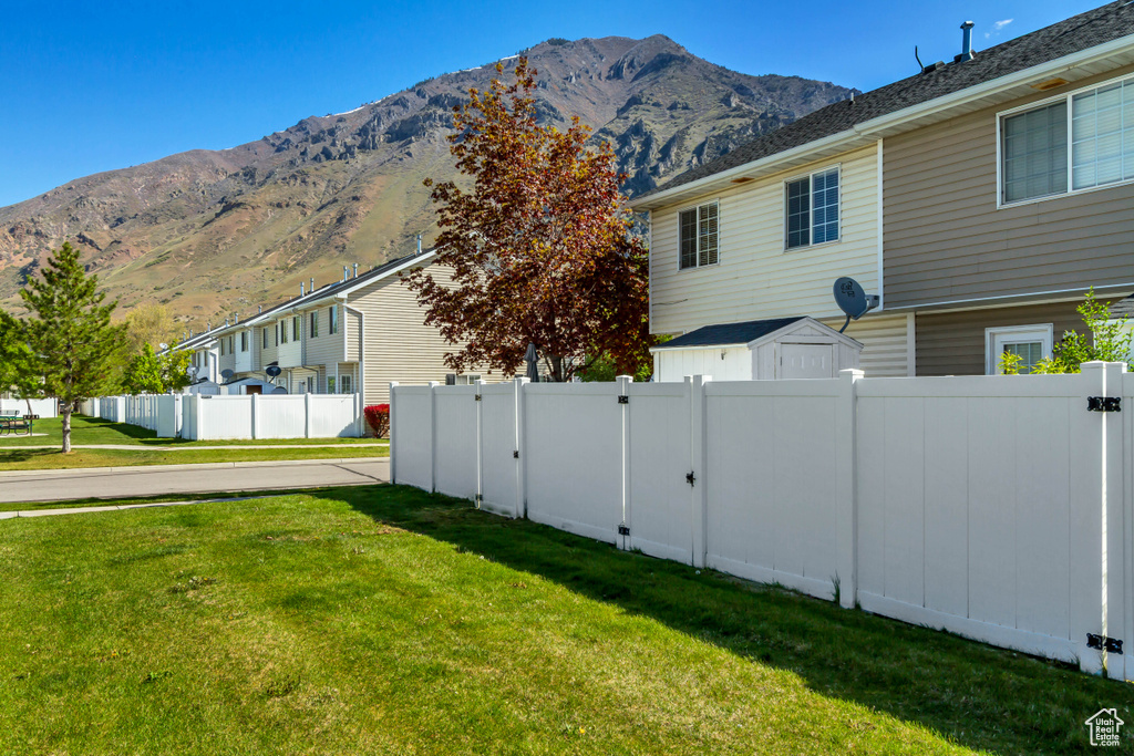 View of side of home with a yard, a residential view, a mountain view, and fence