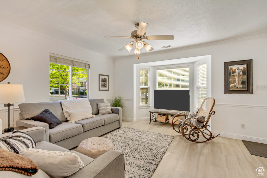 Living room featuring wood finished floors, visible vents, crown molding, ceiling fan, and baseboards