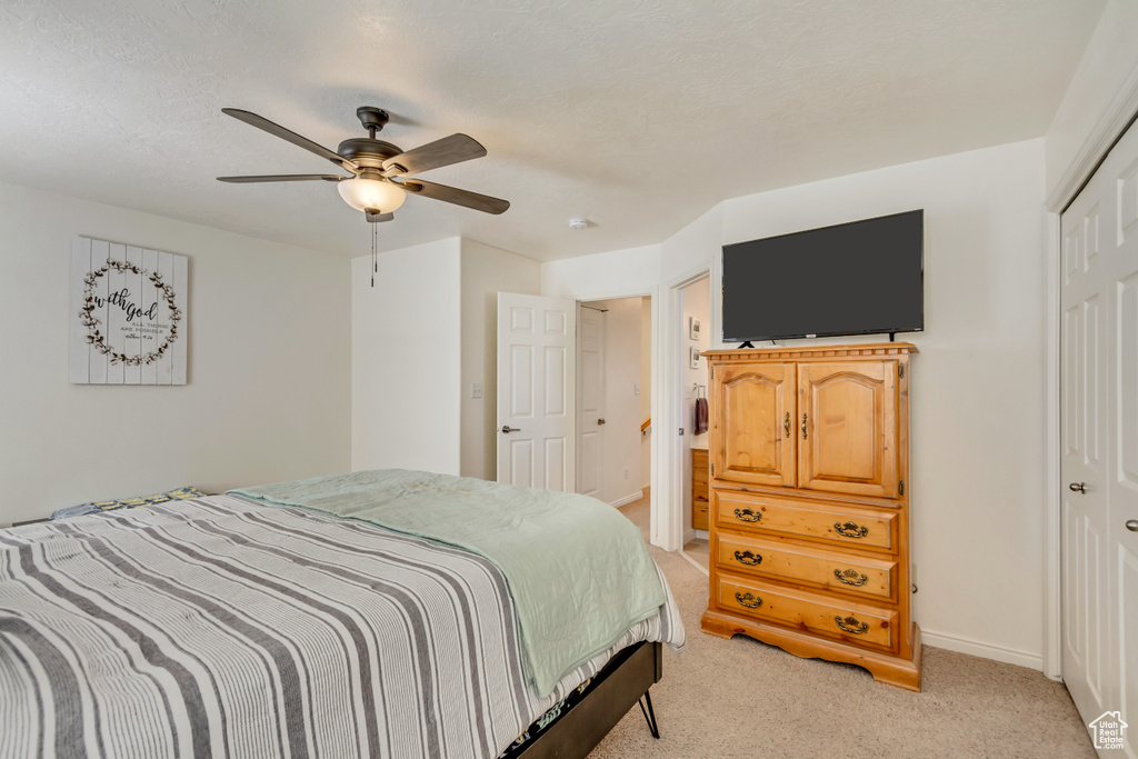 Bedroom featuring baseboards, light carpet, a closet, and a ceiling fan
