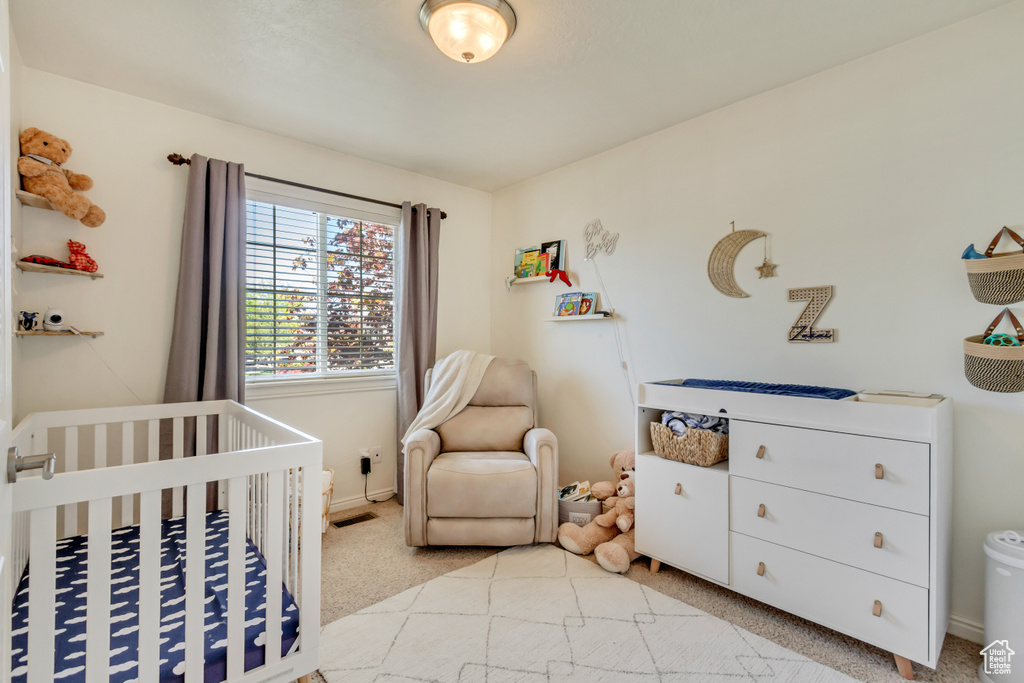 Bedroom with light colored carpet, a nursery area, and visible vents