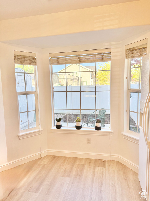 Unfurnished room with light wood-style floors, baseboards, and a healthy amount of sunlight