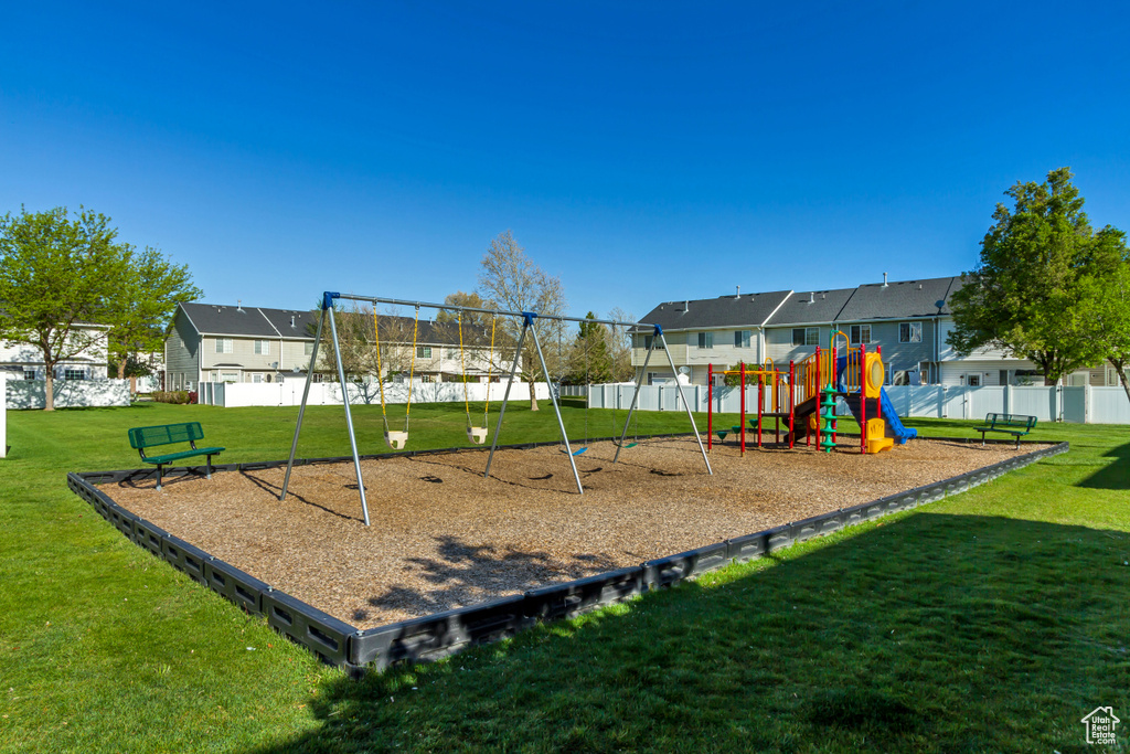 Communal playground with a yard, fence, and a residential view