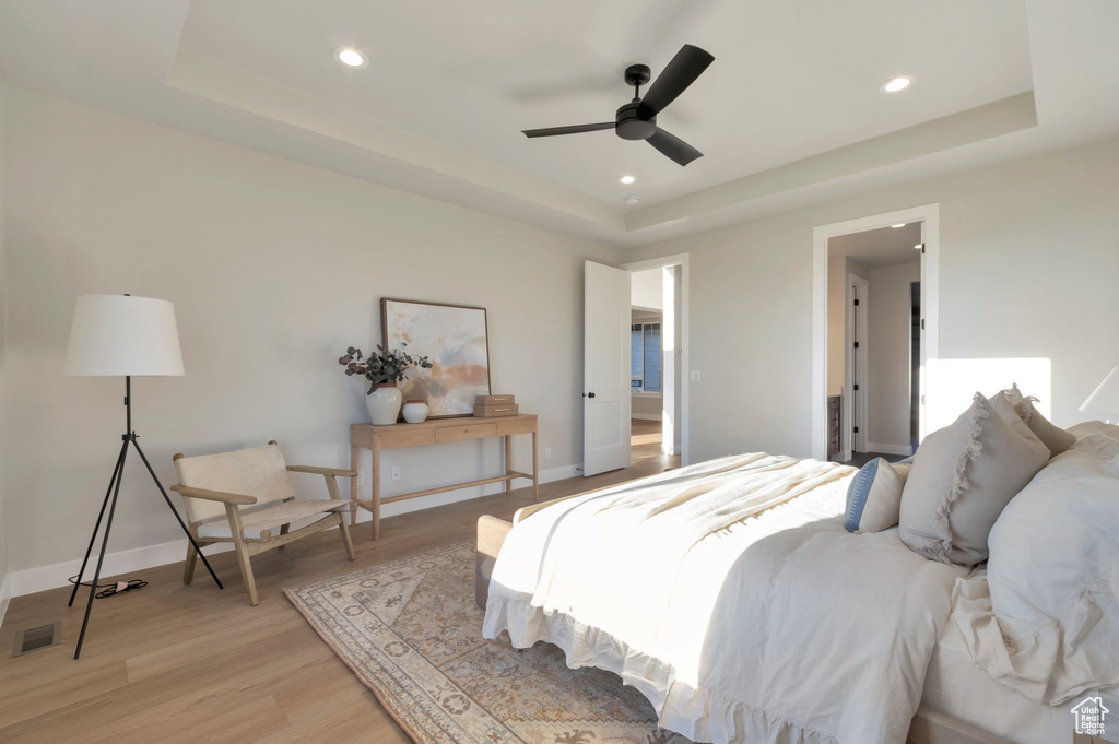 Bedroom featuring light wood-style flooring, a tray ceiling, visible vents, baseboards, and recessed lighting