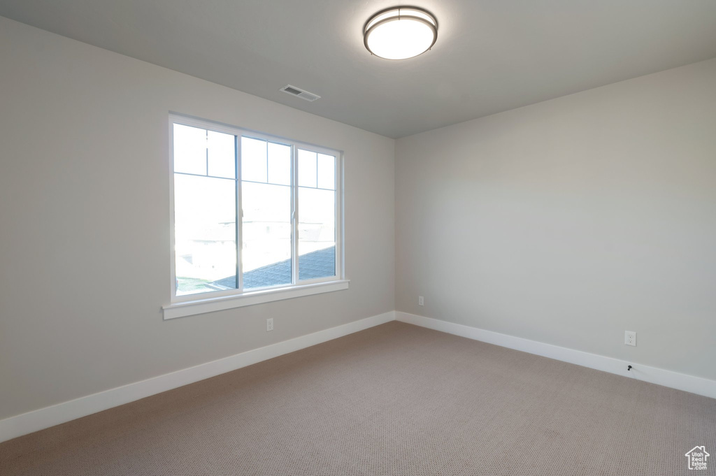Spare room featuring visible vents, baseboards, and carpet floors