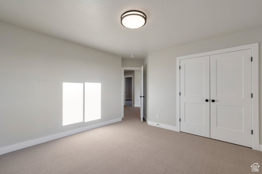 Unfurnished bedroom featuring a closet, baseboards, and carpet floors