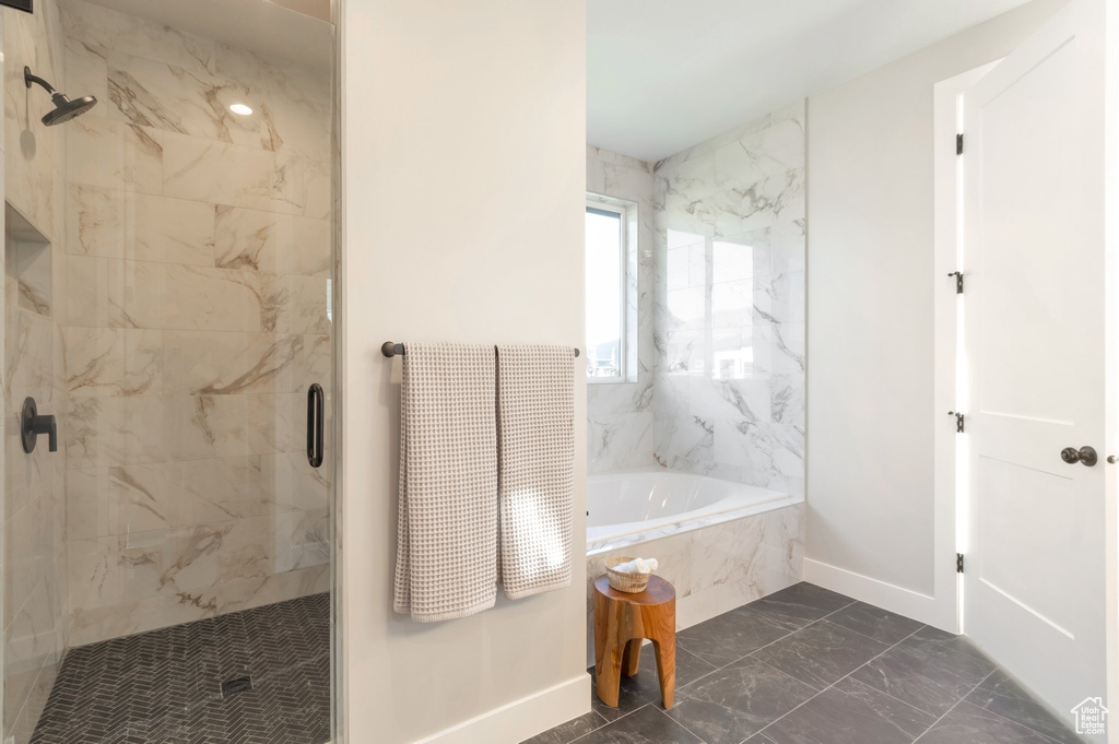 Full bathroom featuring a garden tub, marble finish floor, baseboards, and a stall shower