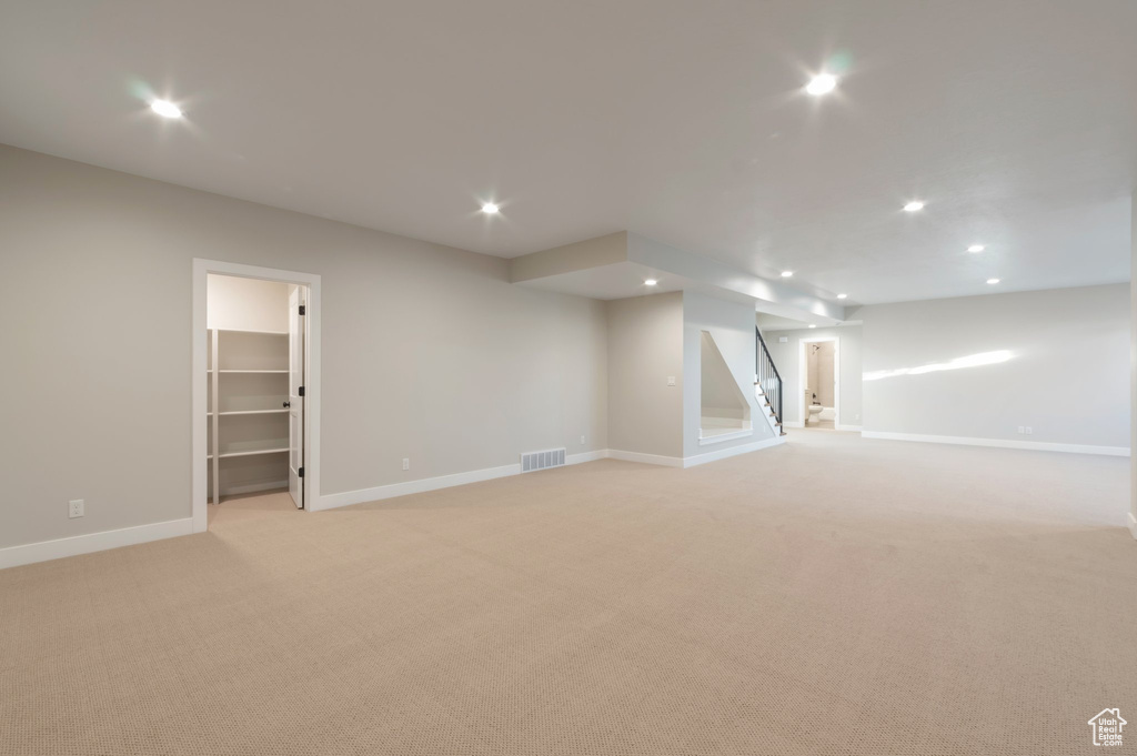 Finished below grade area featuring baseboards, light carpet, visible vents, and recessed lighting