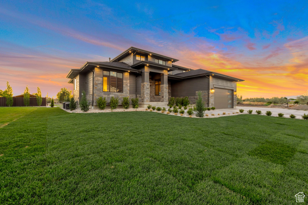 Prairie-style home featuring fence, an attached garage, stone siding, and a front yard