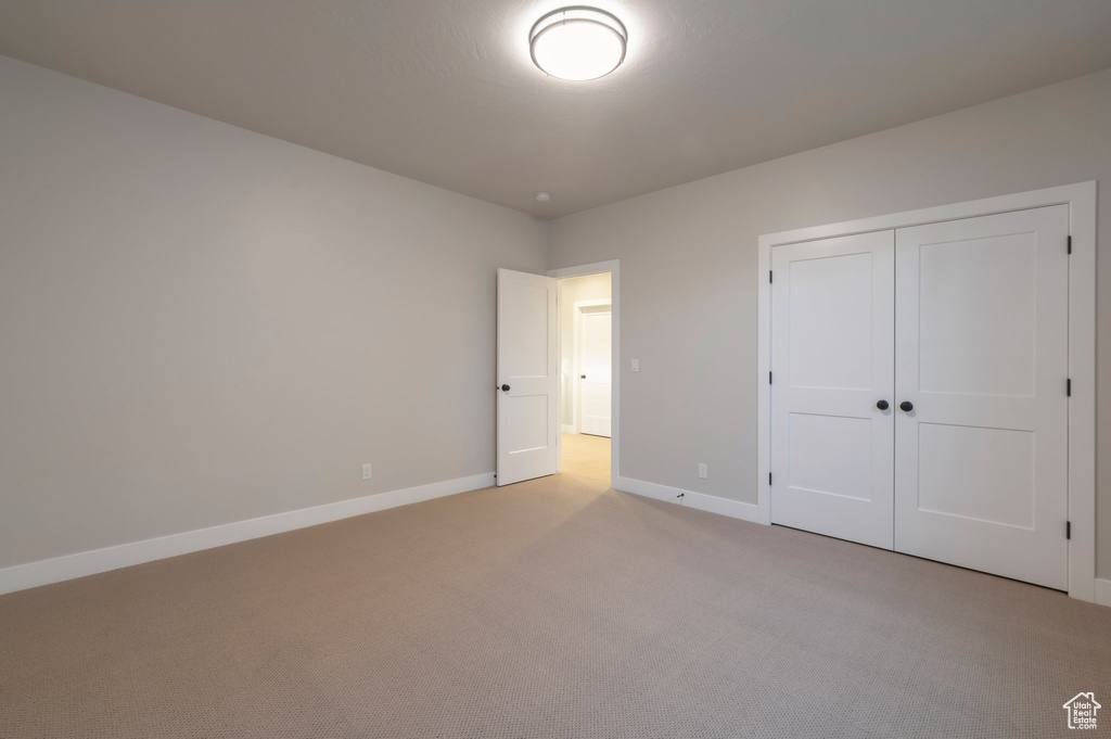 Unfurnished bedroom with carpet flooring, a closet, and baseboards
