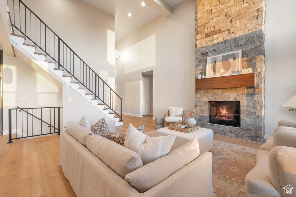 Living area featuring hardwood / wood-style floors, a fireplace, stairway, a high ceiling, and baseboards