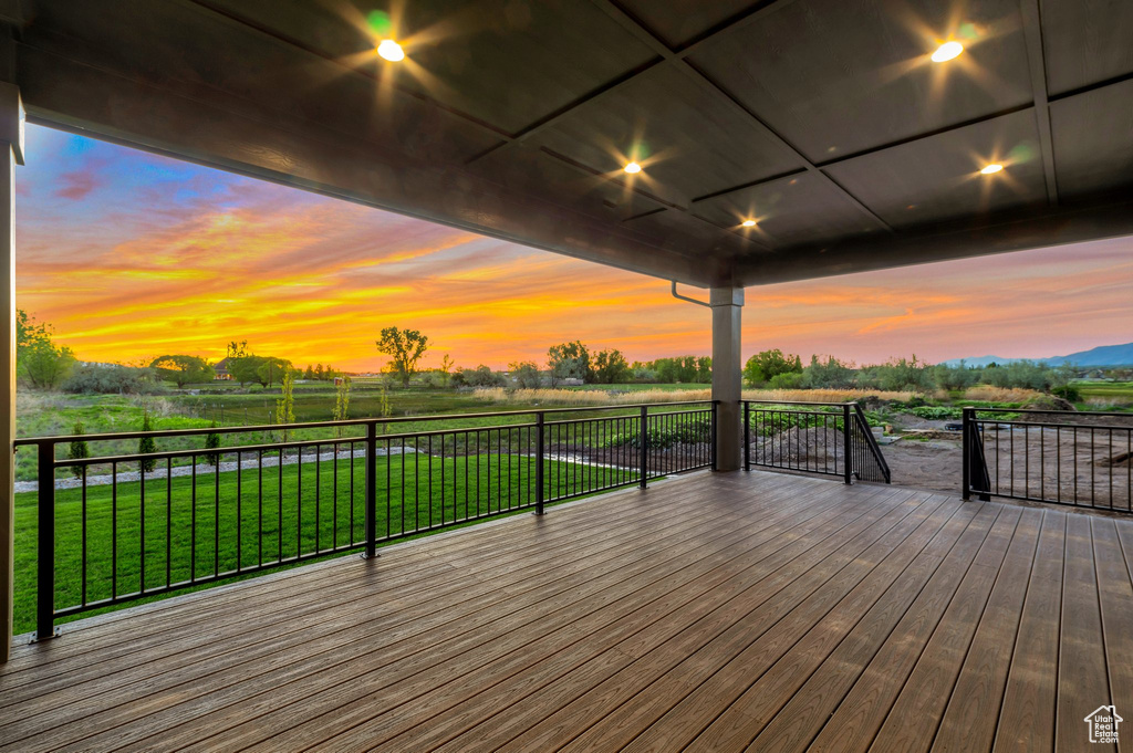 Deck at dusk with a rural view and a lawn