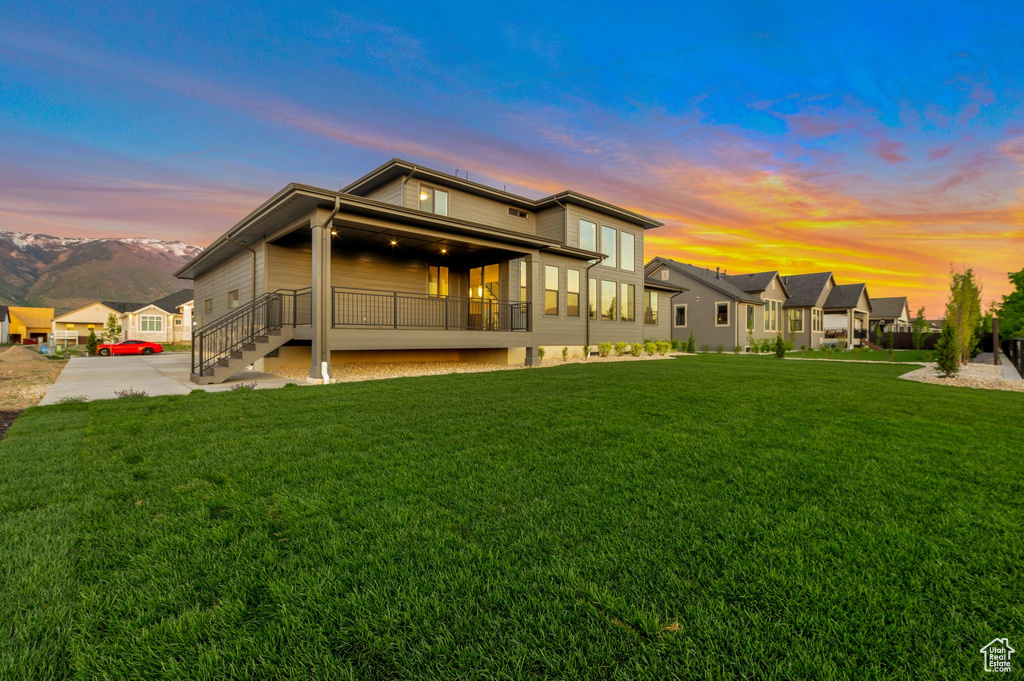 Back of property at dusk featuring a lawn