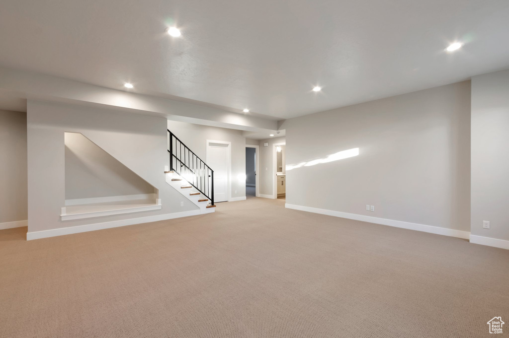 Basement with light colored carpet, stairway, baseboards, and recessed lighting