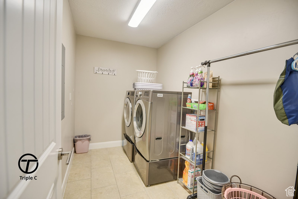 Washroom featuring tile patterned floors, washing machine and clothes dryer, baseboards, and laundry area