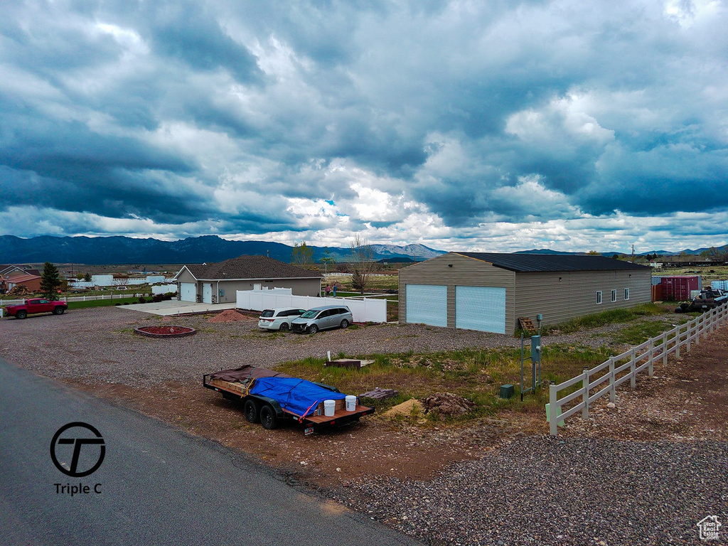 View of front facade featuring a mountain view, an outdoor structure, fence, and a detached garage