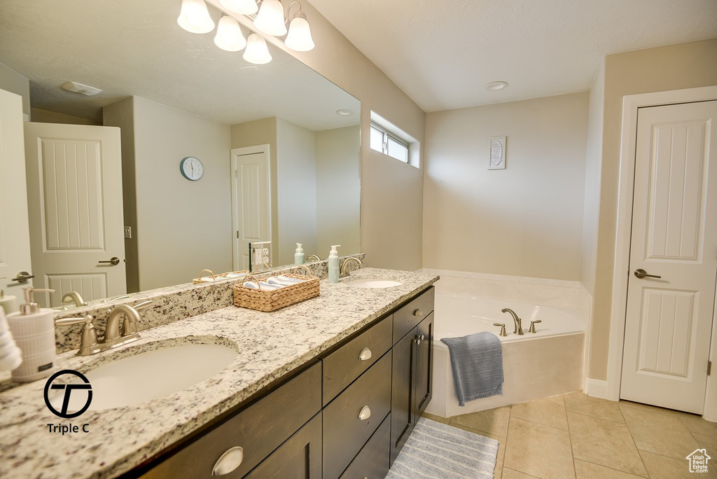 Full bathroom featuring a bath, tile patterned floors, double vanity, and a sink