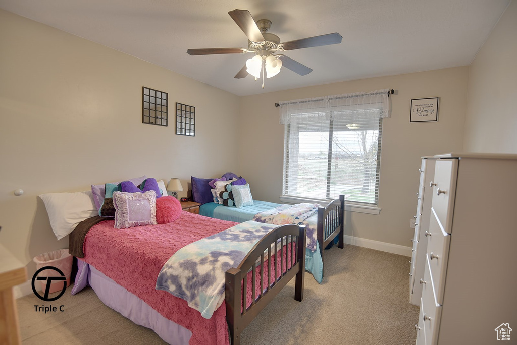 Bedroom with light colored carpet, baseboards, and ceiling fan