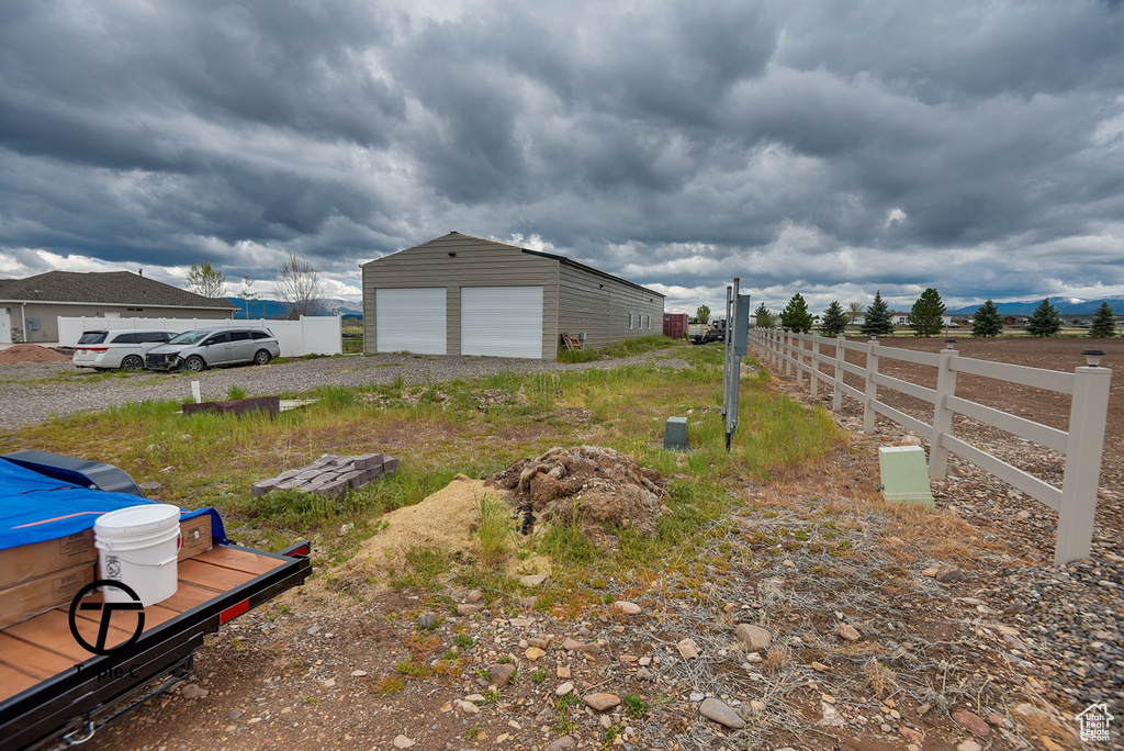 View of yard with fence, a detached garage, and an outdoor structure