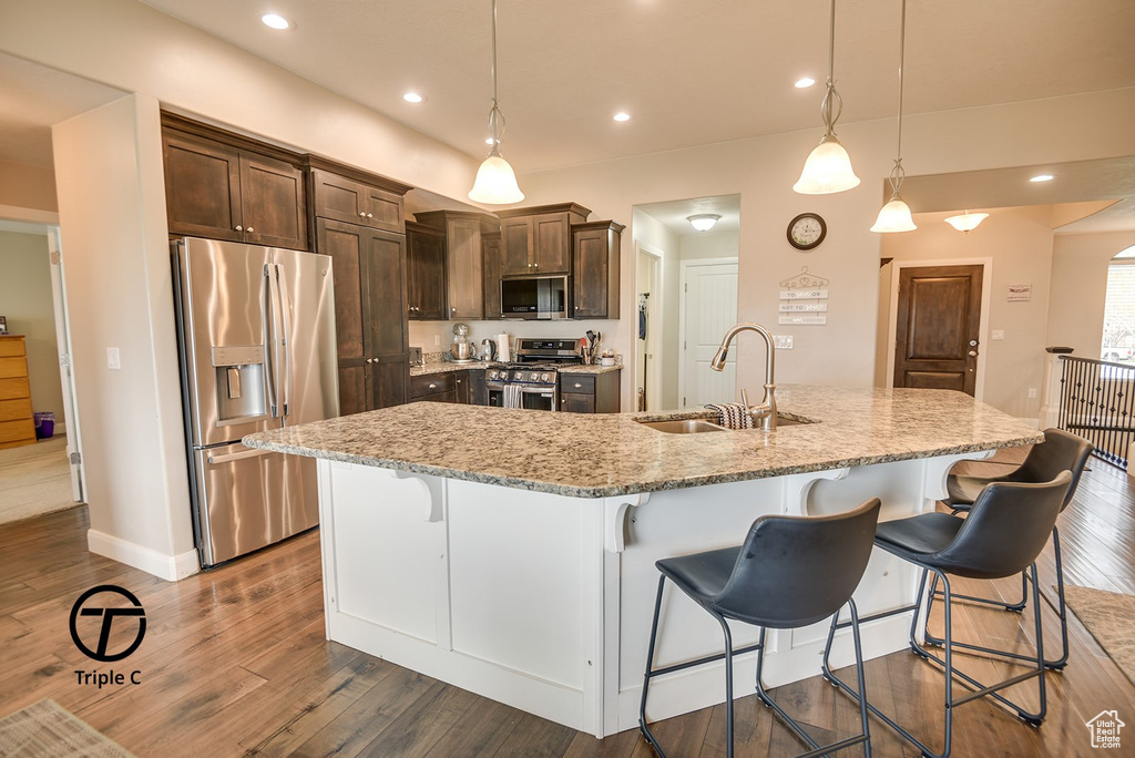 Kitchen with dark brown cabinetry, stainless steel appliances, dark wood-style floors, and a sink