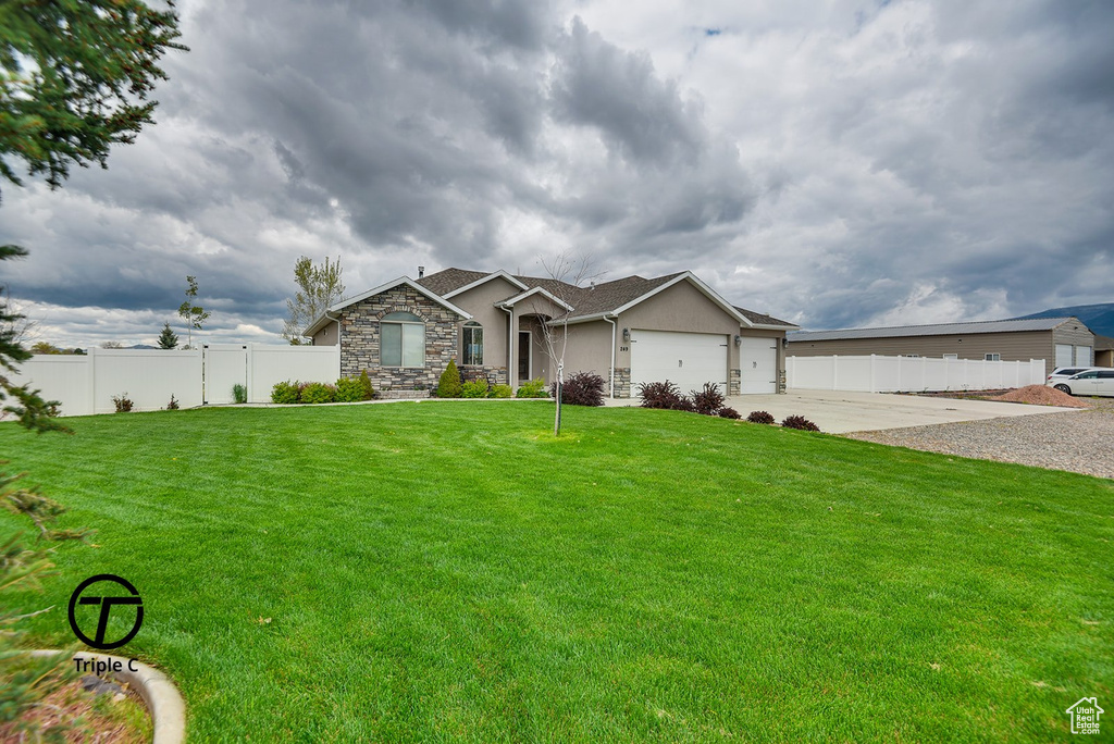 Ranch-style home featuring an attached garage, stone siding, concrete driveway, and stucco siding