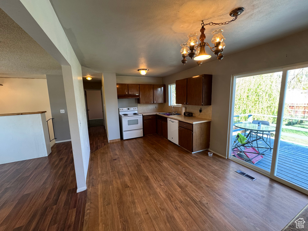 Kitchen with white appliances, visible vents, light countertops, dark wood-style floors, and a notable chandelier