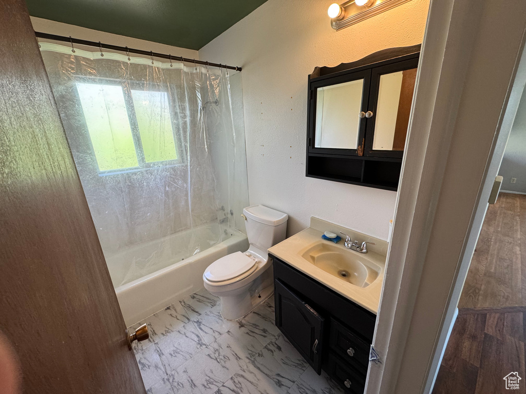 Bathroom with vanity, toilet, and shower / bath combo with shower curtain