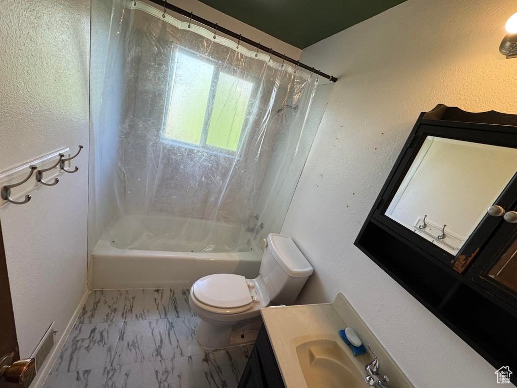 Bathroom featuring marble finish flooring, toilet, shower / bath combo, and vanity