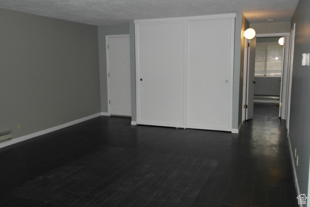 Interior space featuring dark wood finished floors, a textured ceiling, and baseboards