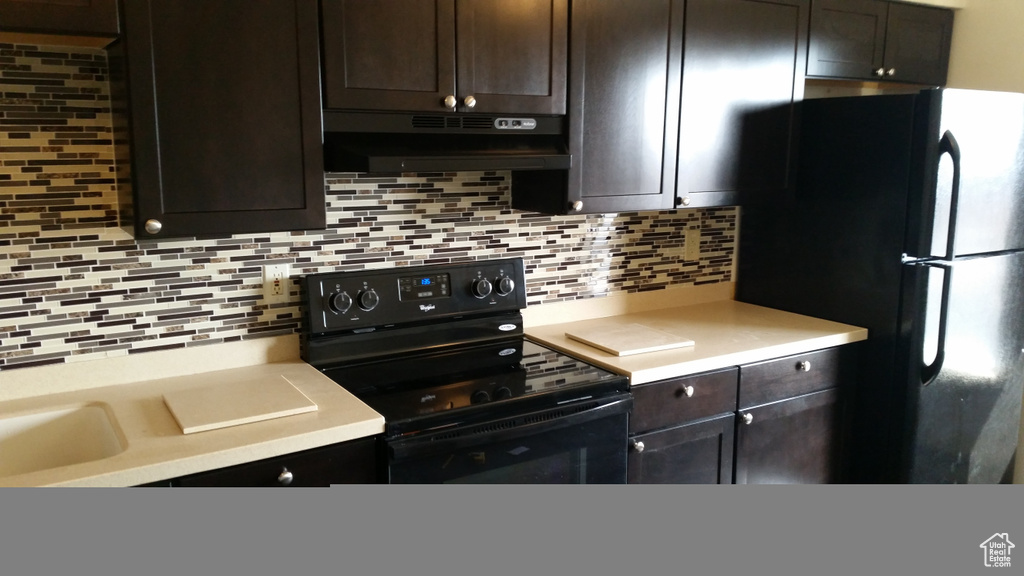 Kitchen with backsplash, black appliances, light countertops, and under cabinet range hood