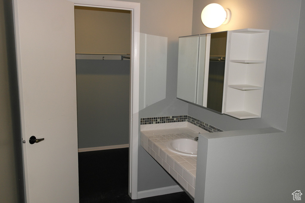 Bathroom with a walk in closet, backsplash, and vanity