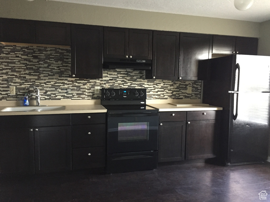 Kitchen featuring black appliances, under cabinet range hood, decorative backsplash, and a sink