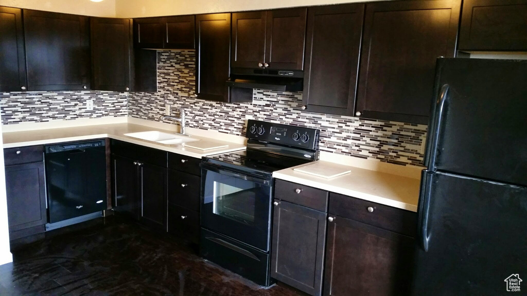 Kitchen with under cabinet range hood, backsplash, a sink, and black appliances