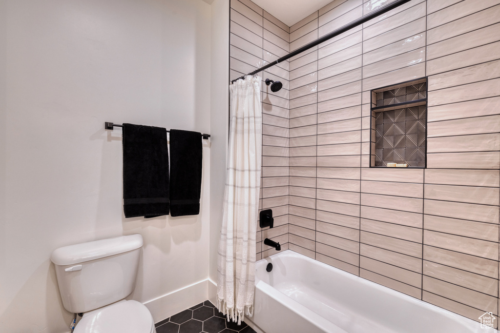 Bathroom with shower / bath combo with shower curtain, baseboards, tile patterned floors, and toilet
