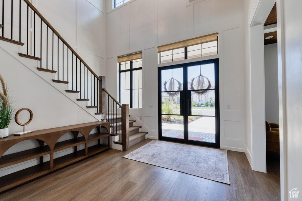 Entryway featuring stairs, a towering ceiling, and wood finished floors