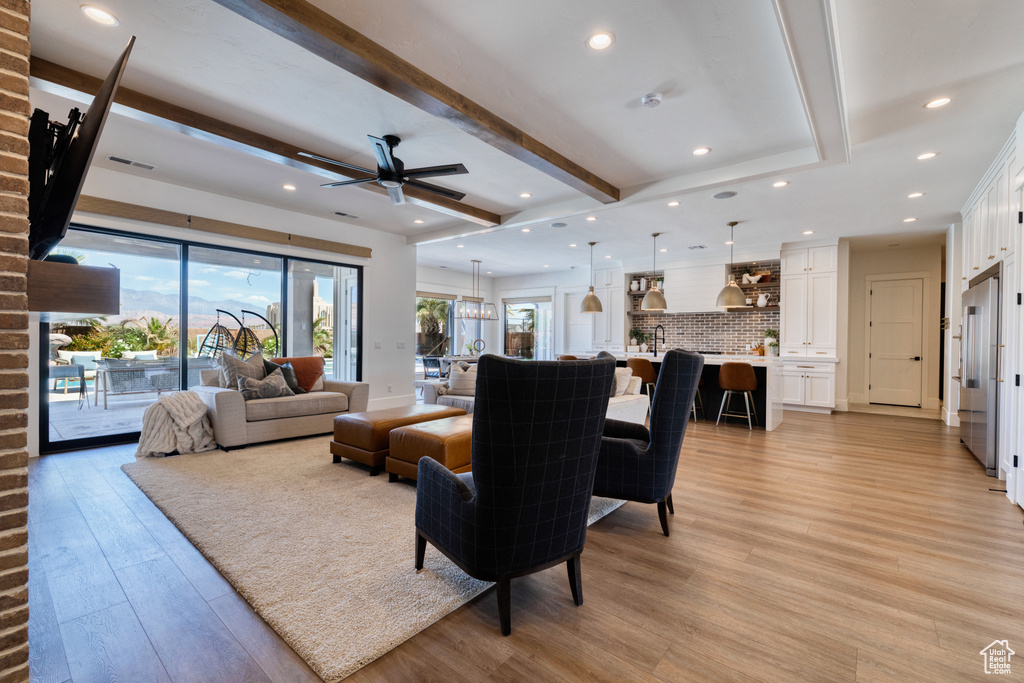Living area featuring light wood-type flooring, a ceiling fan, recessed lighting, and beamed ceiling