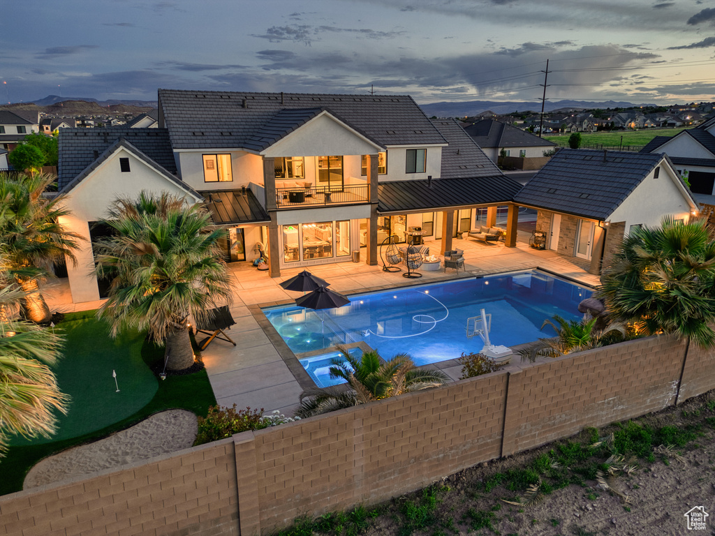 Back of property featuring stucco siding, a fenced backyard, a balcony, a standing seam roof, and metal roof