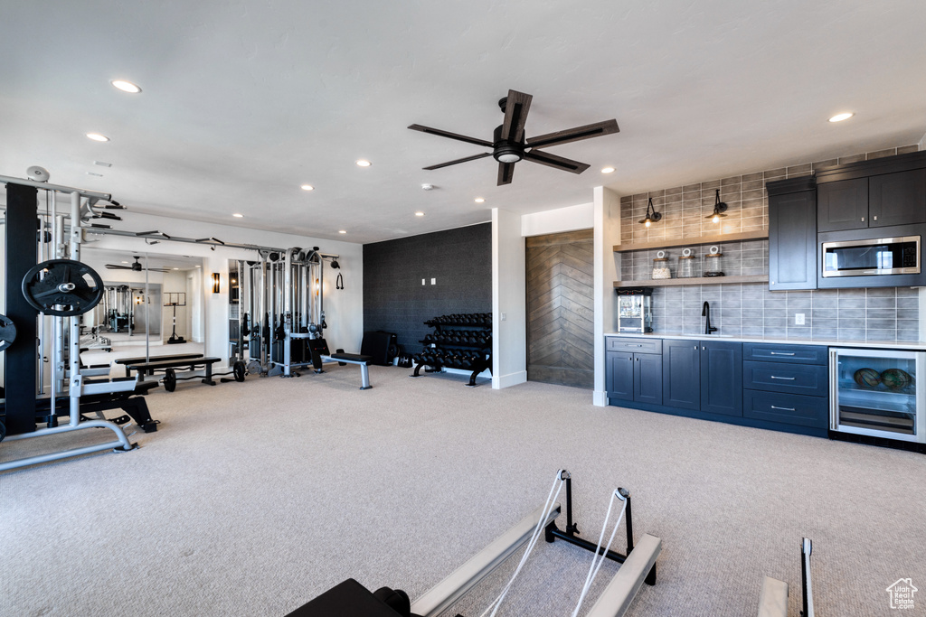 Interior space with beverage cooler, stainless steel microwave, recessed lighting, and light carpet