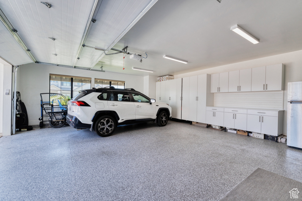 Garage with freestanding refrigerator and a garage door opener