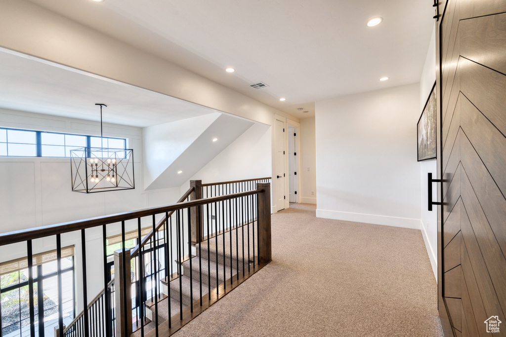 Corridor featuring carpet floors, visible vents, recessed lighting, a notable chandelier, and an upstairs landing