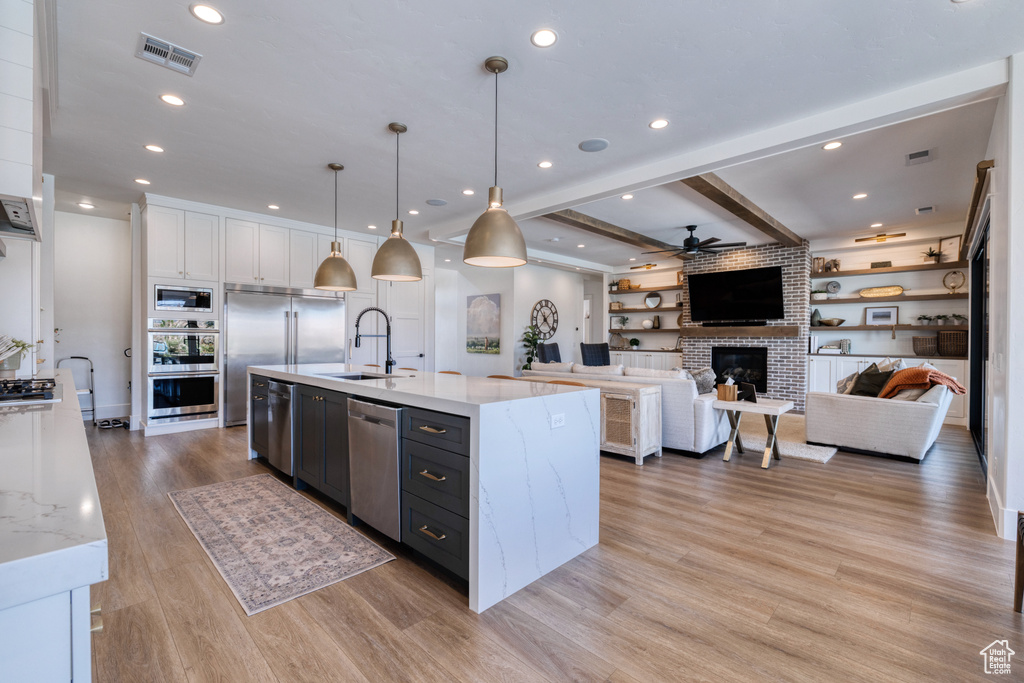 Kitchen featuring light wood-style floors, ceiling fan, white cabinetry, a sink, and appliances with stainless steel finishes