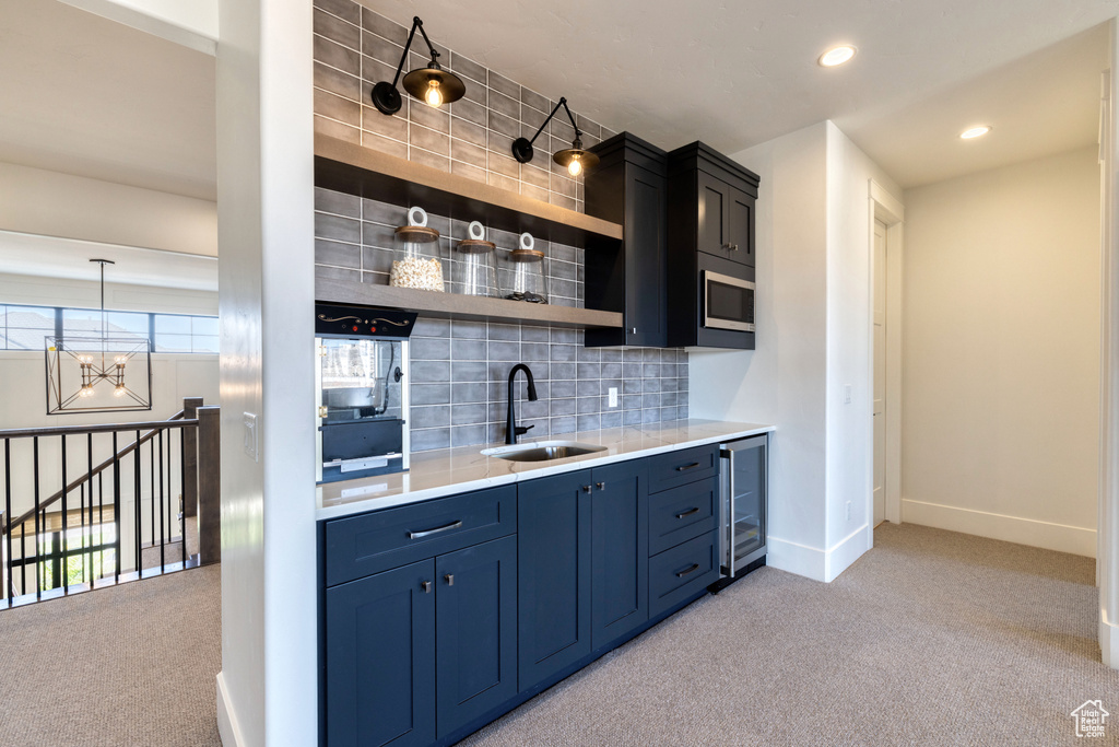Bar featuring beverage cooler, baseboards, light colored carpet, and a sink