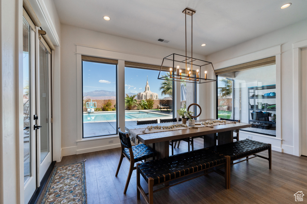 Dining space featuring a healthy amount of sunlight, a notable chandelier, dark wood-type flooring, and visible vents