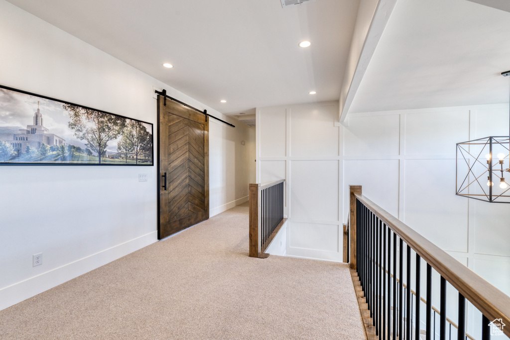 Corridor featuring recessed lighting, a barn door, carpet, and a decorative wall