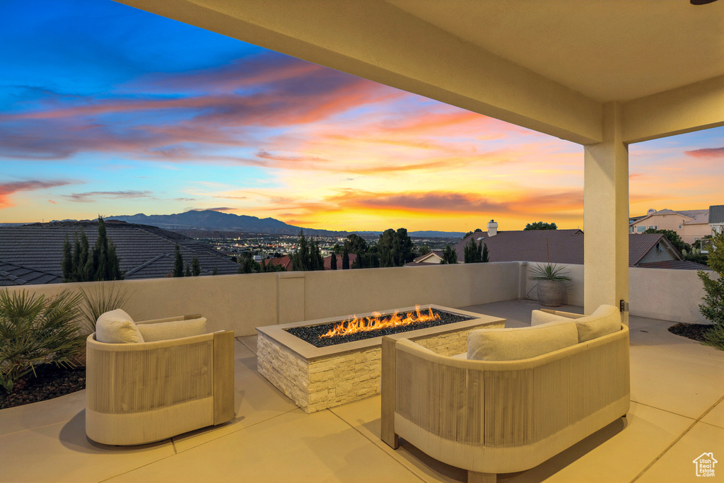 Patio terrace at dusk with an outdoor living space with a fire pit, a mountain view, and fence