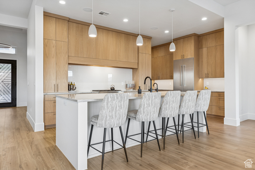 Kitchen featuring light wood-style flooring, high quality fridge, and modern cabinets