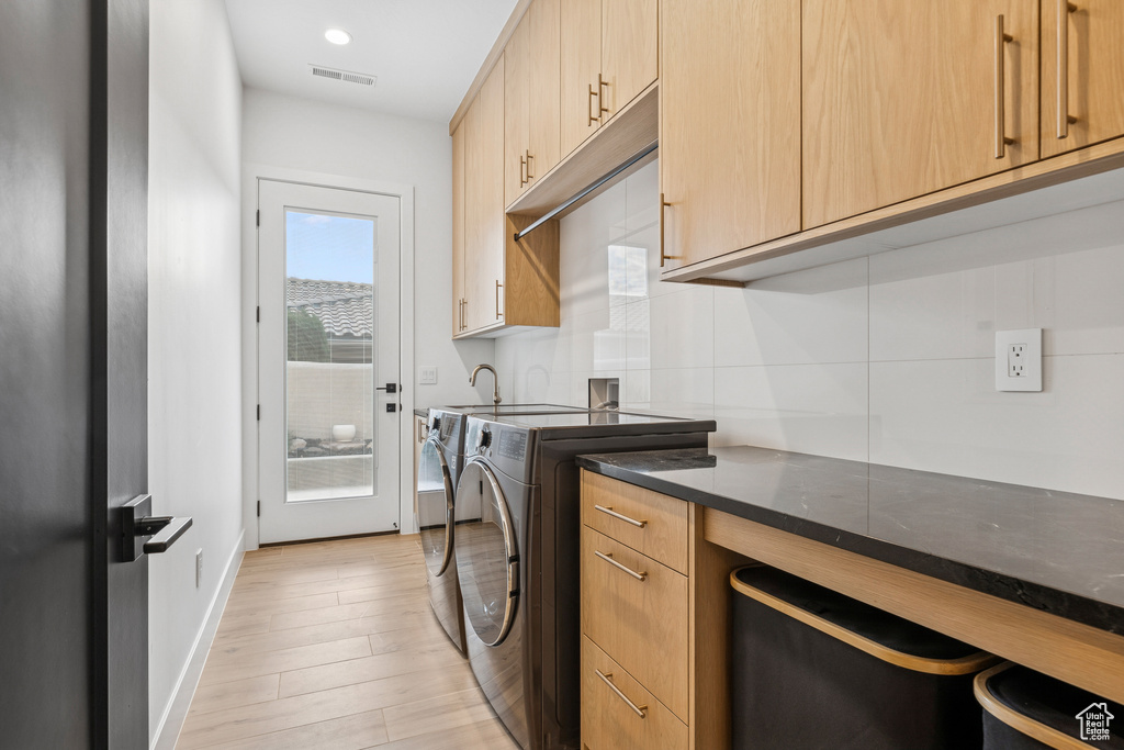 Washroom with cabinet space, visible vents, washing machine and clothes dryer, baseboards, and light wood-style floors