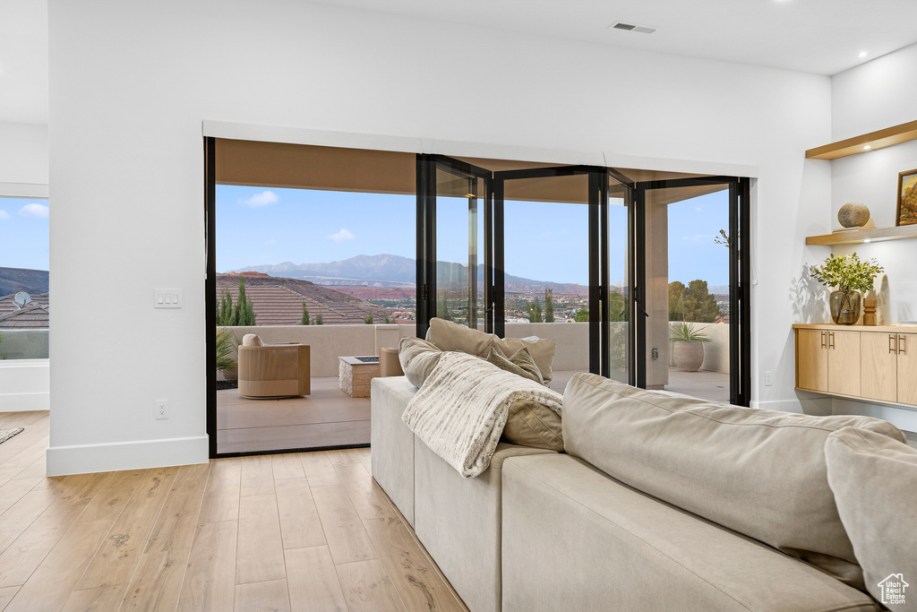 Bedroom with a mountain view, baseboards, visible vents, light wood-style floors, and access to exterior